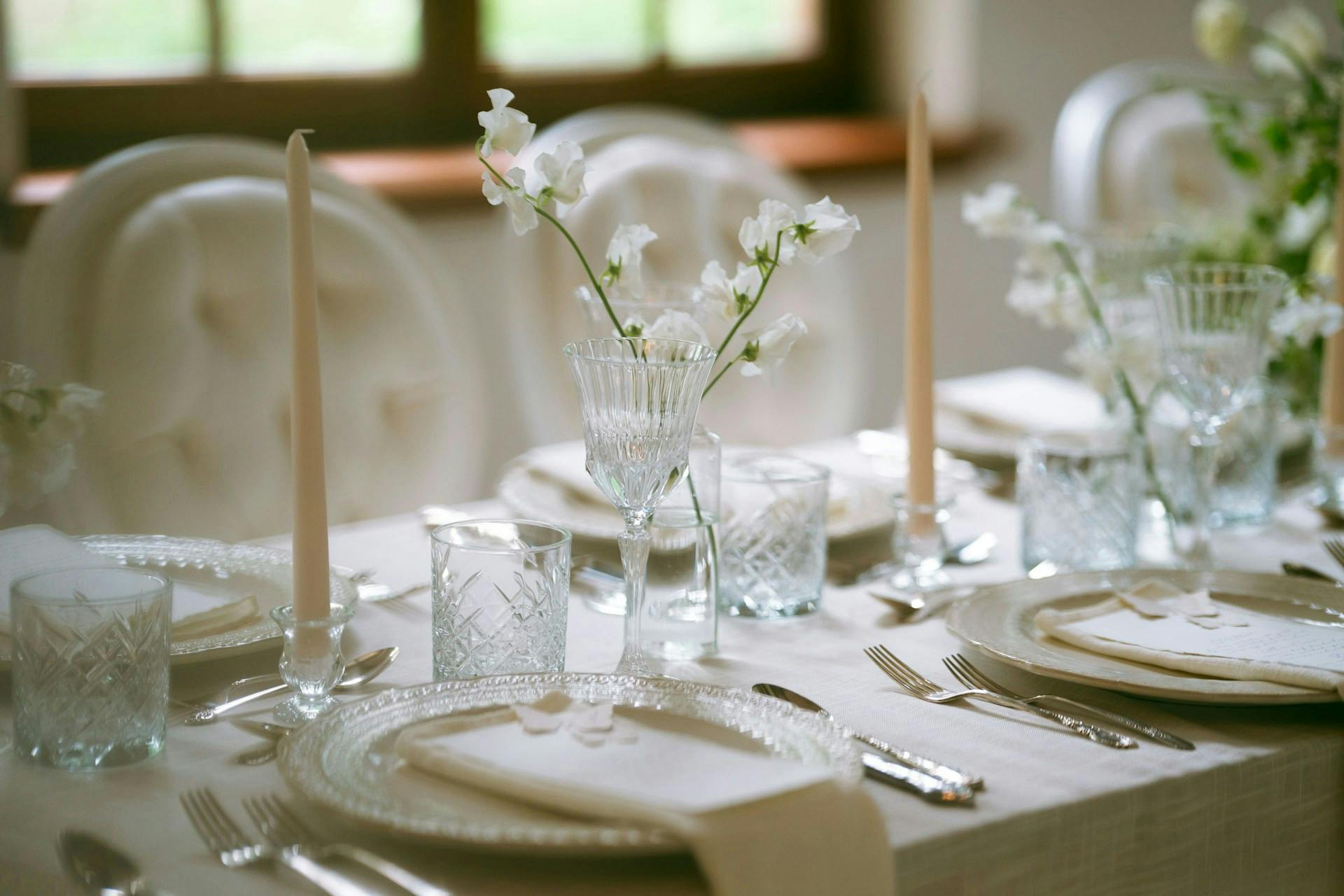 Gedeckter Tisch mit weißer Tischdecke und Kerzen.