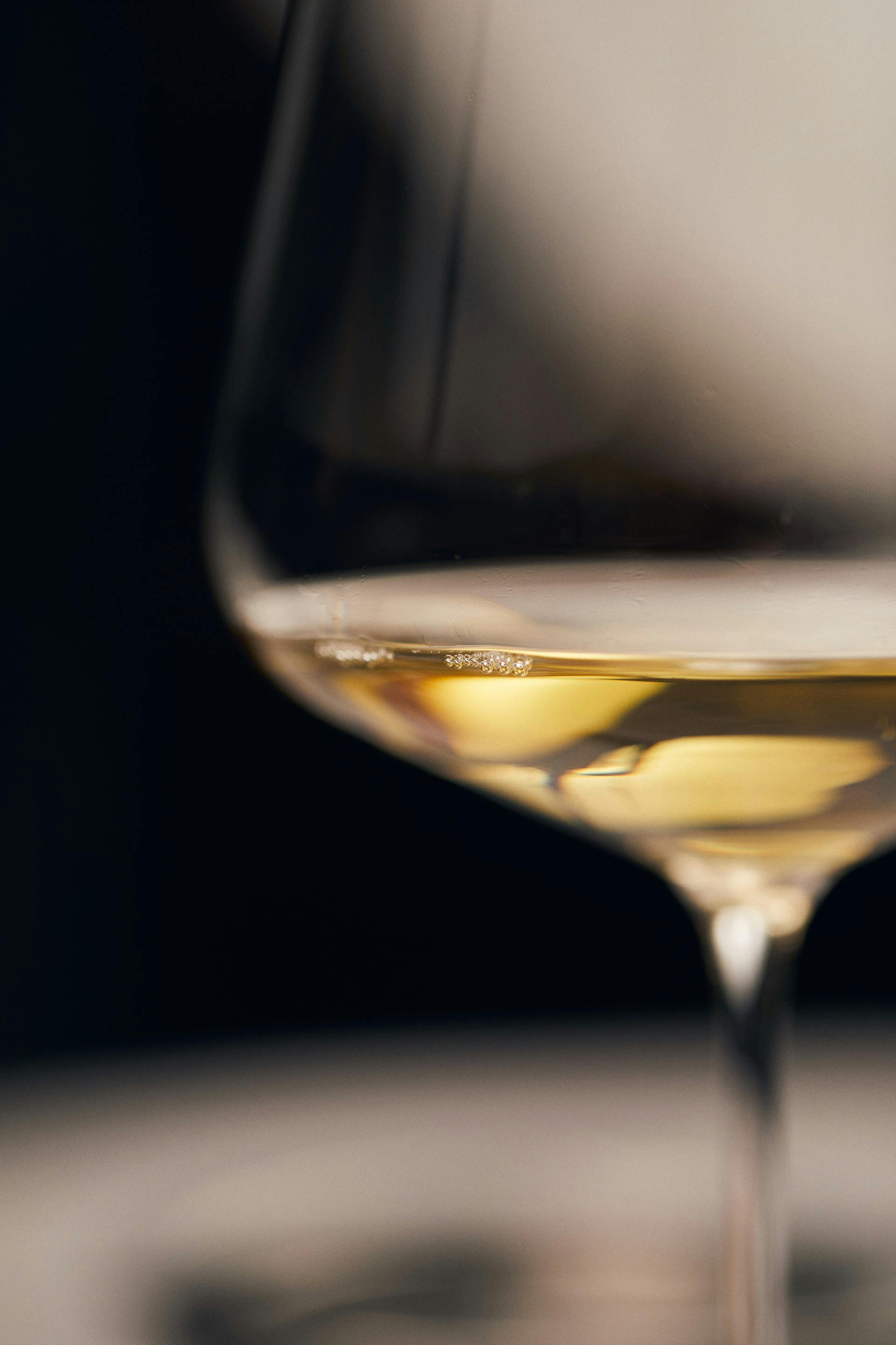 Nahaufnahme Weißweinglas mit gelblicher Flüssigkeit drin