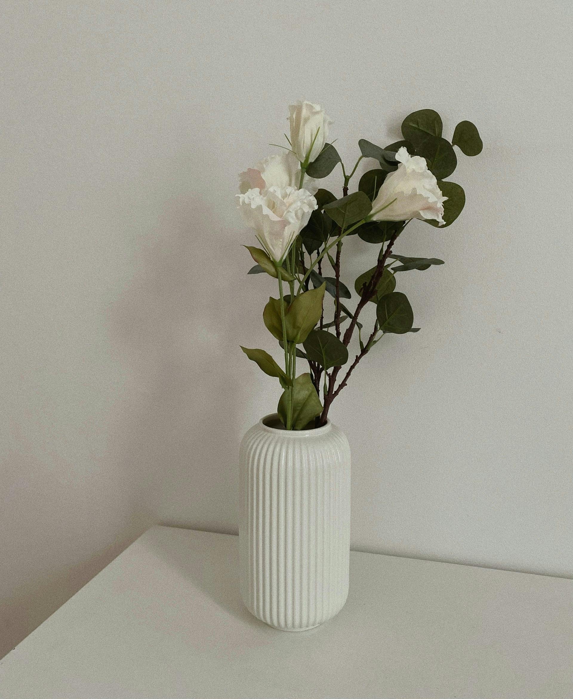 Blumen stehen in einer weißen Blumenvase