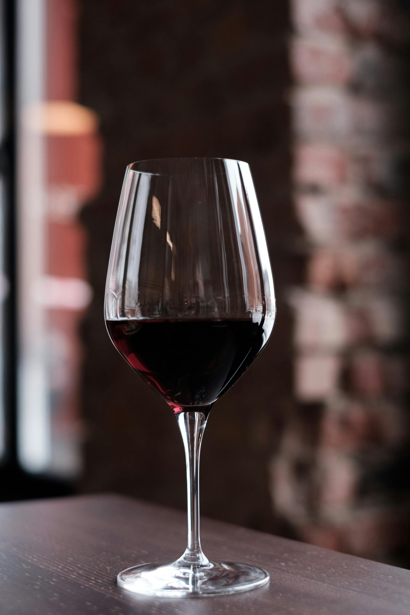 Glas Rotwein vor roter Steinwand