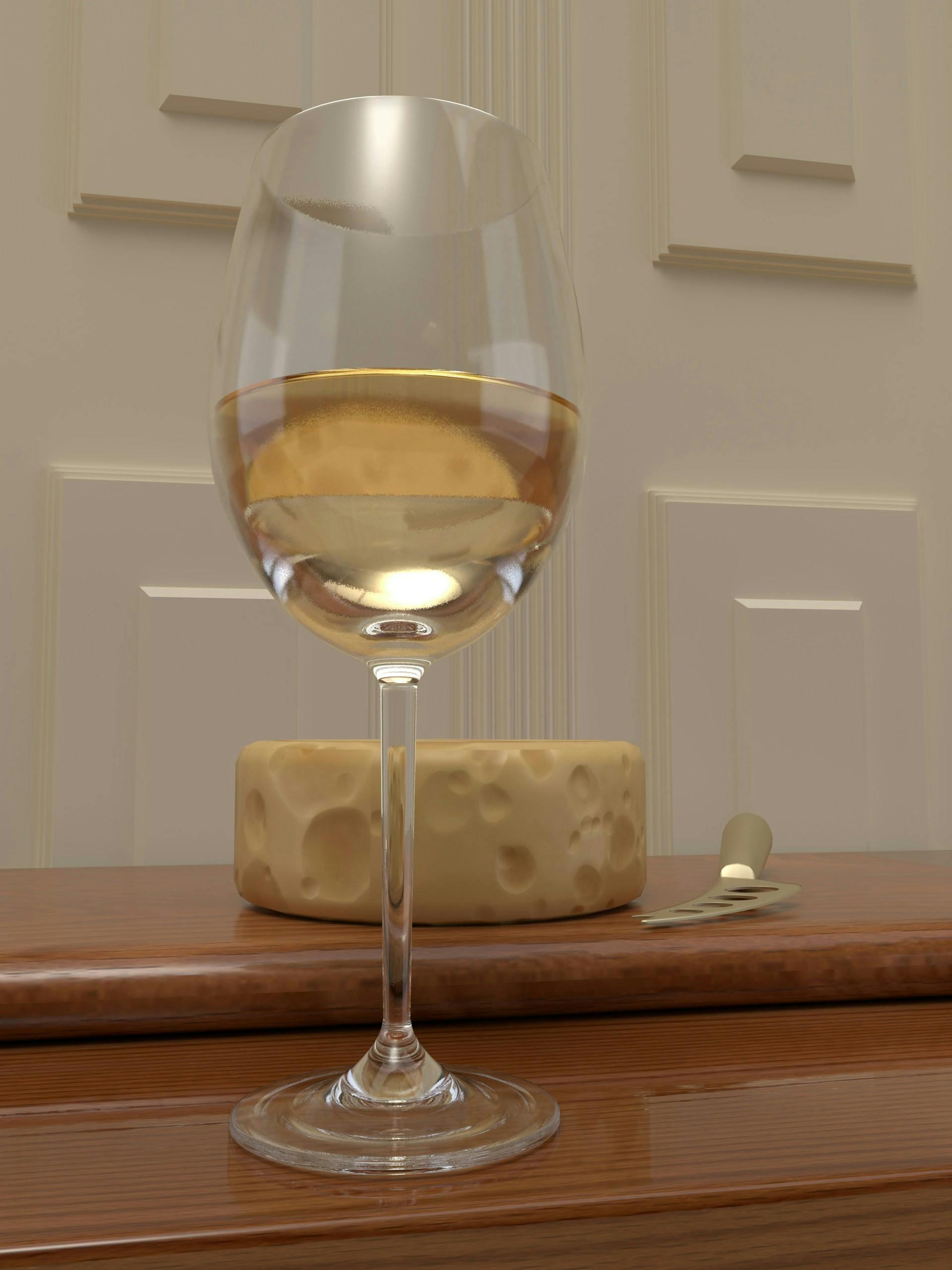 Weinglas mit heller Flüssigkeit darin steht vor einem Käseblock