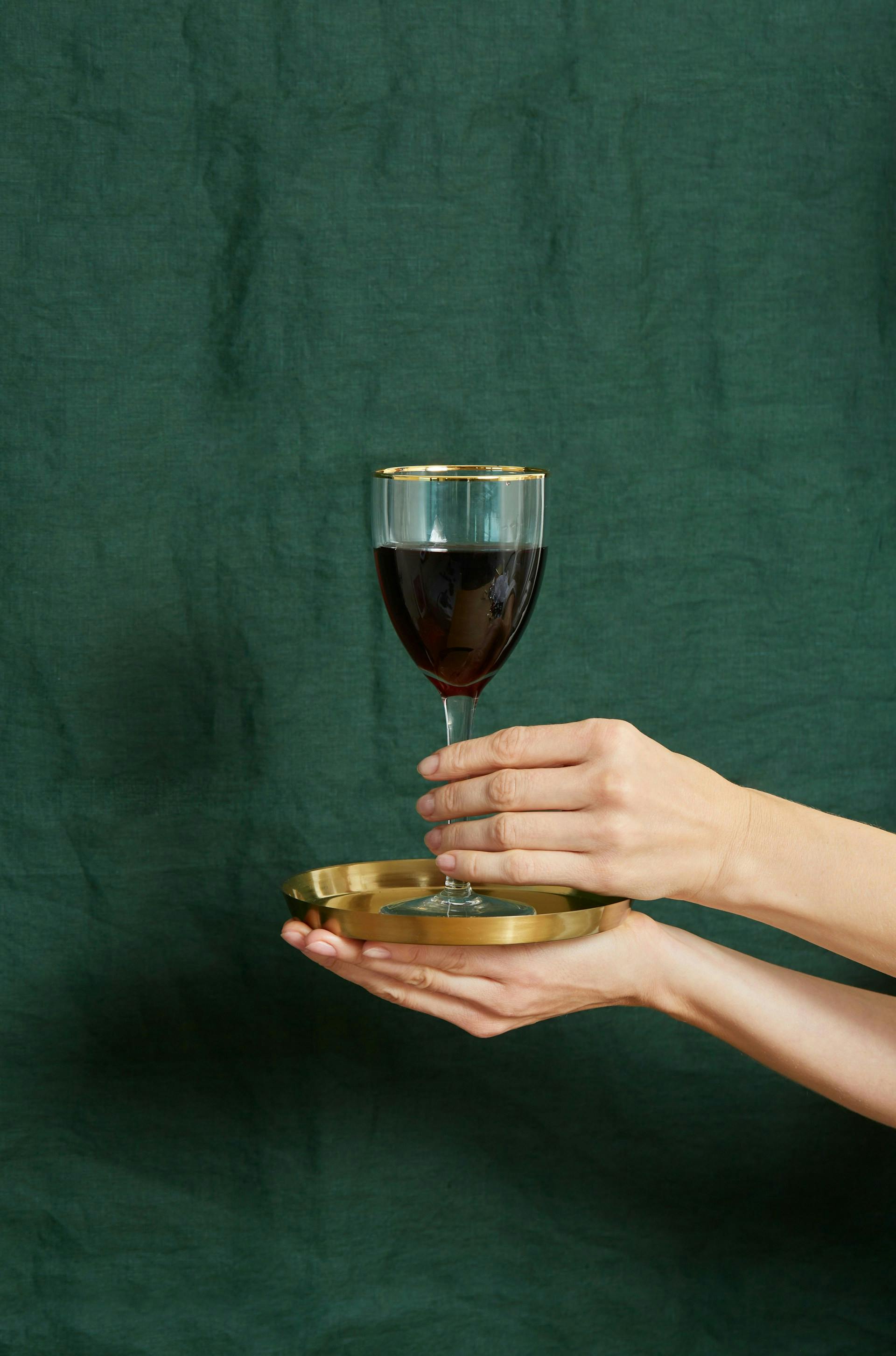 Rote Flüssigkeit in einem Glas auf einem goldenen Tellerchen