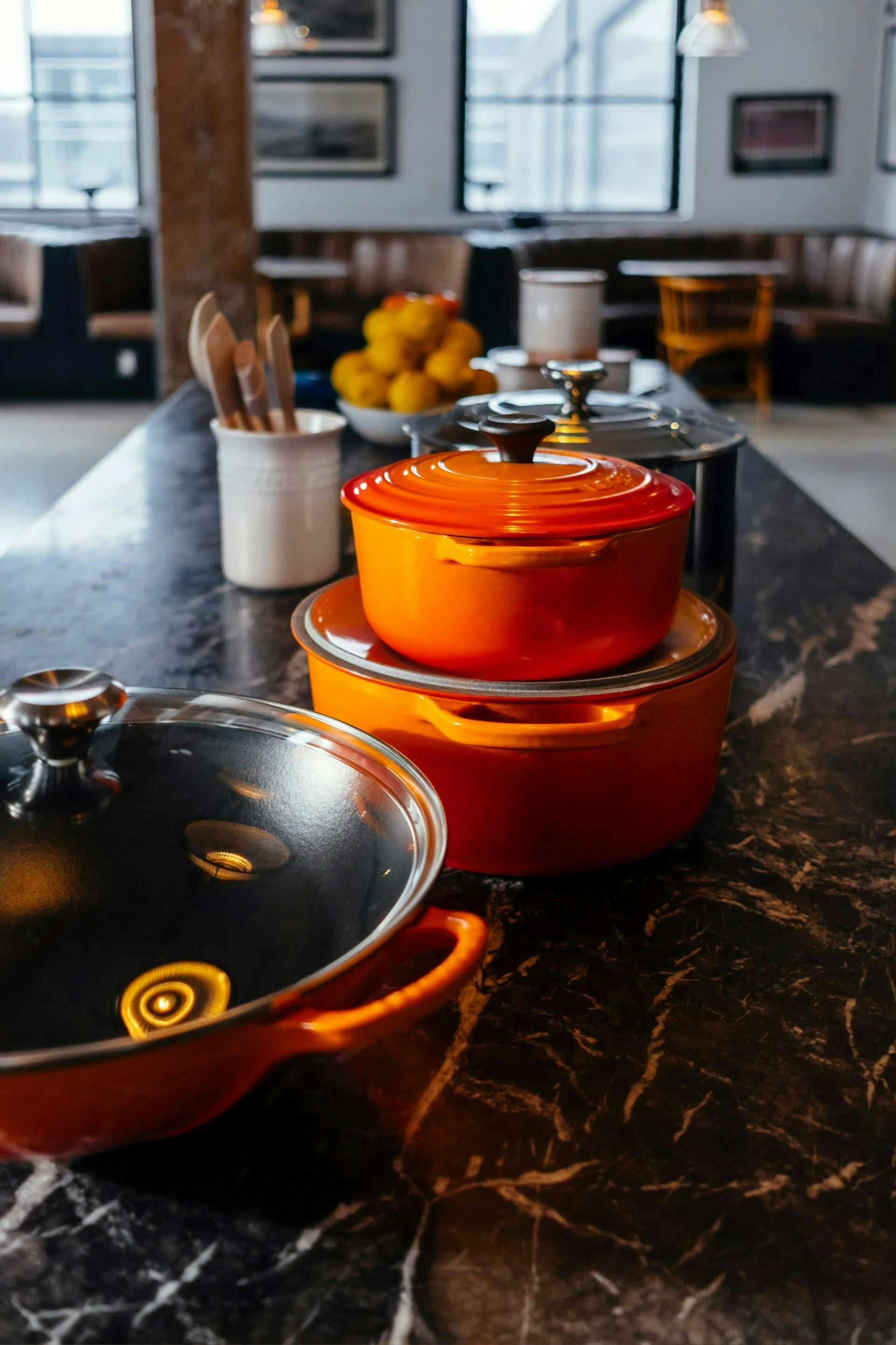 Orangefarbene Kochtöpfe auf einer dunklen Küchenarbeitsplatte 