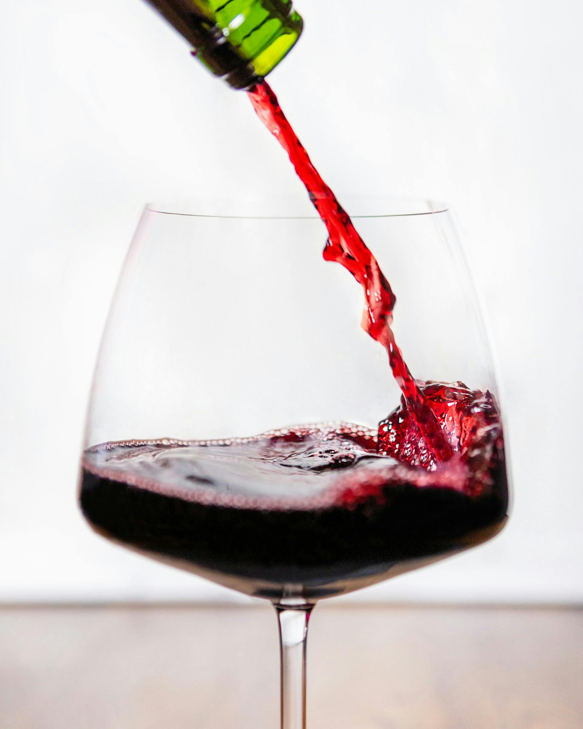 Rotwein wird aus Flasche in Glaß eingeschenkt