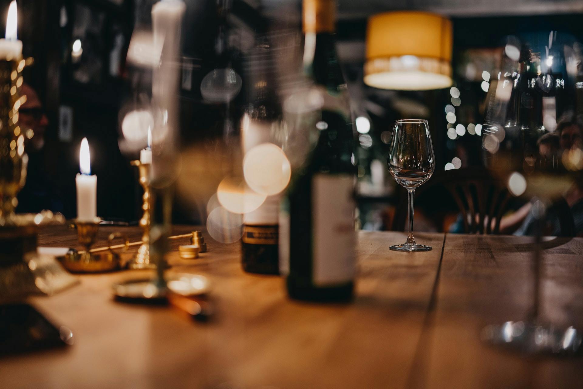 Weinflasche auf Holztisch, Weingläser und Kerzenlicht 